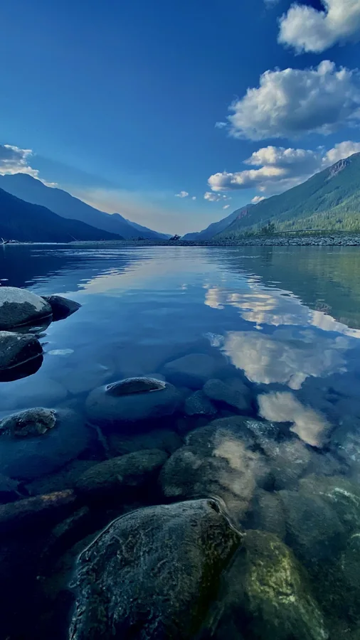 Mountain lake with mirror reflections, clouds and foreground rocks