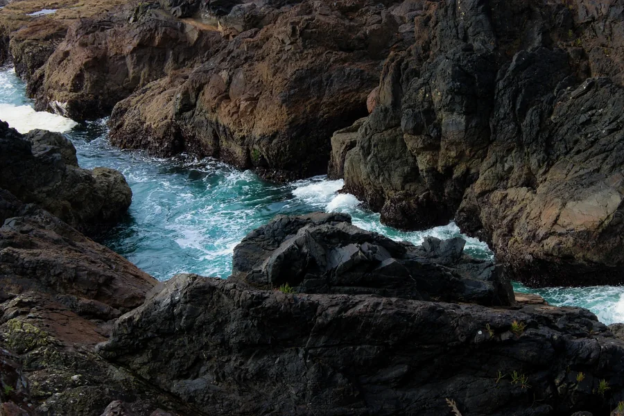 Turquoise ocean water rushing through a rugged rocky channel