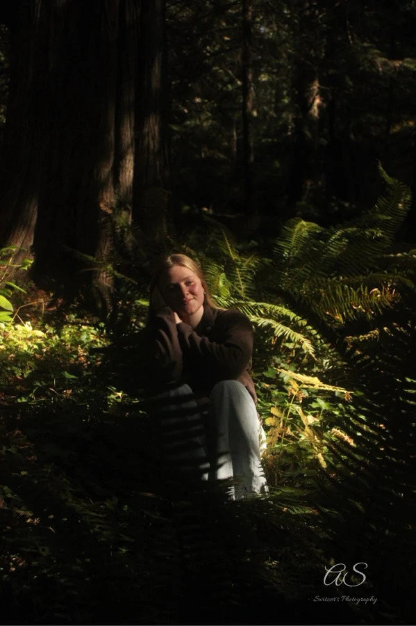 Young woman among ferns glowing in filtered sunlight