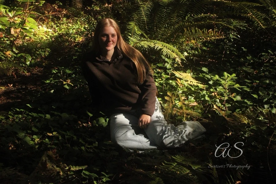 Young woman resting among green ferns in soft shade